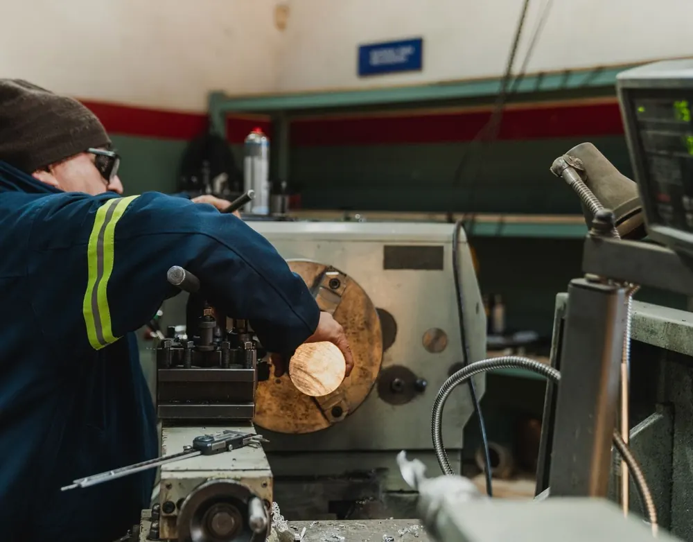 Symbolbild: Arbeiter in Schutzjacke an einer Drehmaschine in der Werkstatt